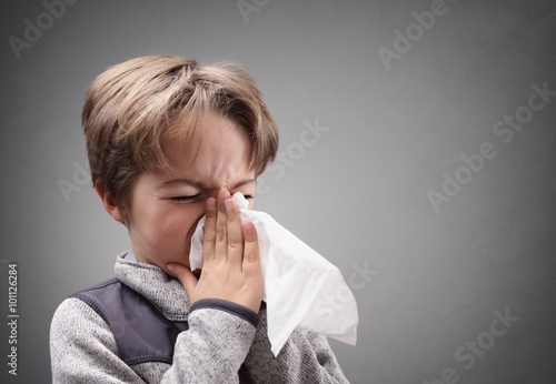 Boy with a tissue blowing his nose