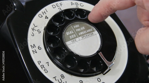 Close up of a man's hand dialling a number on a mid 20th century UK rotary dial telephone. Numbers 1 through 0 are dialled in turn with a pause between each one with hand out of shot. photo