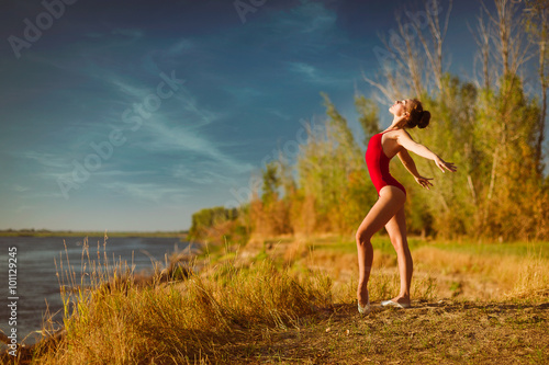 The young ballerina in a red bathing suit dances on the tips of