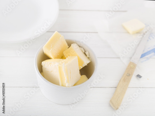 Fotografija chopped butter in a white bowl on light background