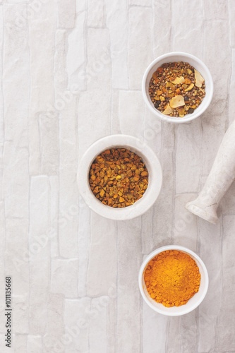 Turmeric pieces and curry. Turmeric pieces in a mortar with pestle and curry in ceramics bowls