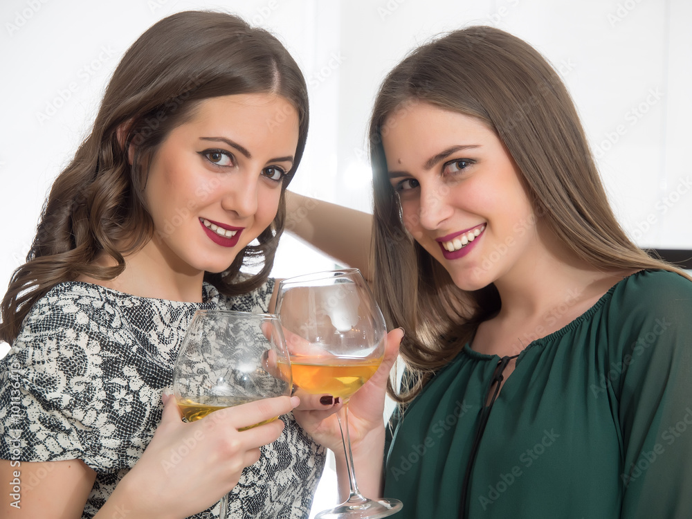 Two beautiful teenage girls drink vine in kitchen Two beautiful teenage girls drink vine in kitchen