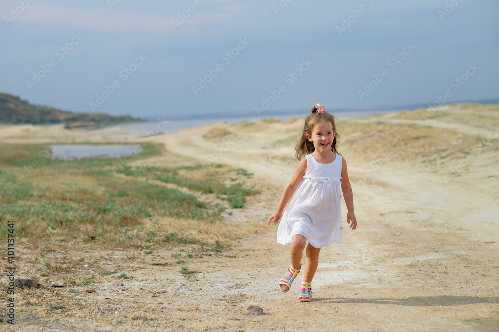 Little girl playing at the summer beach