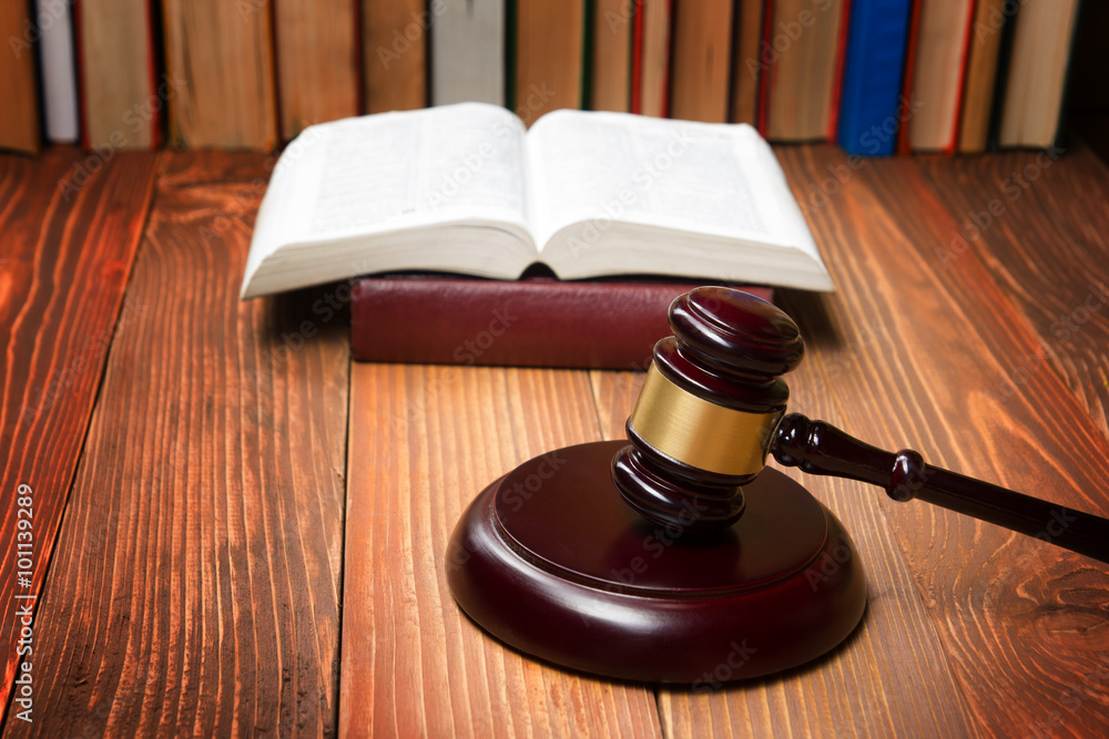 Law book with wooden judges gavel on table in a courtroom or law enforcement office.