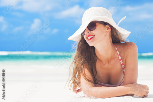 young woman in stripy swimsuit and a hat at tropical beach