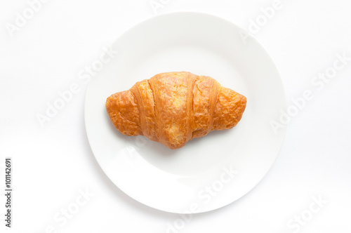 Croissant on white plate, top view. Sweat baked dessert in a dis