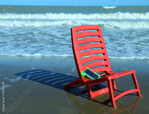chair on the beach with a smartphone closed in the protective wa