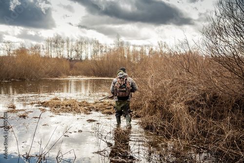 Fotografiet hunter man creeping in swamp during hunting period