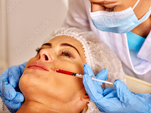 Woman middle-aged in spa salon with doctor. Beauty woman giving anti-ageing injections.