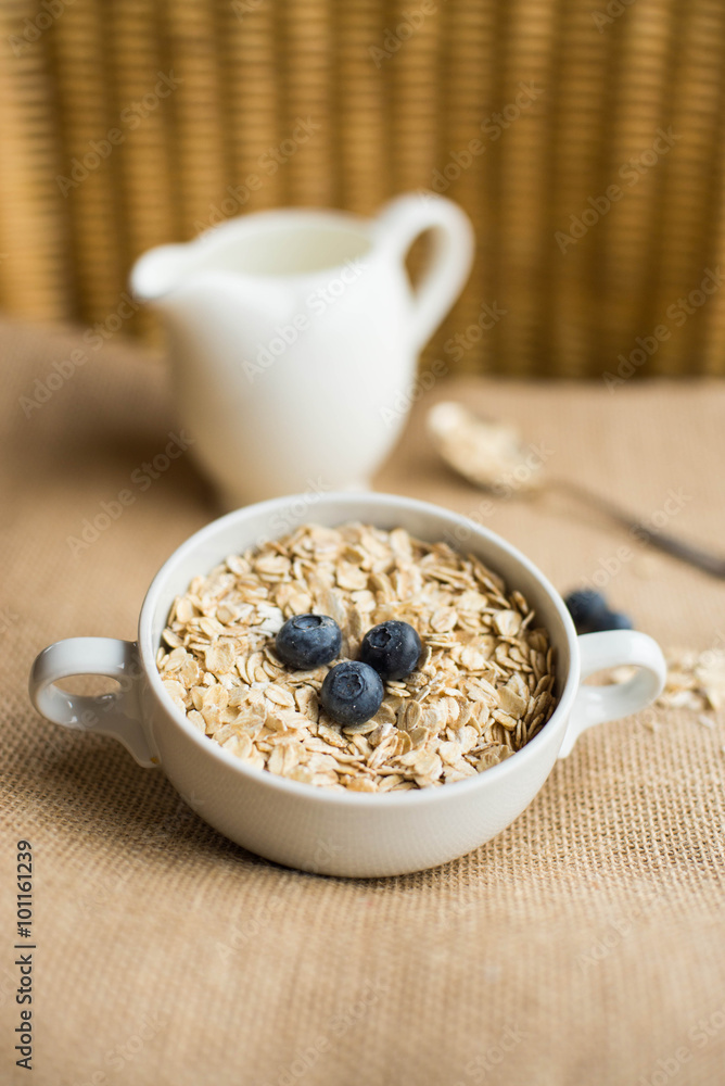 Oatmeal with blueberries and jug of milk on rustic background. Top view. Oatmeal with blueberries and jug of milk on rustic background. Top view.