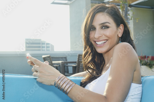 Middle Eastern woman using cell phone on sofa photo
