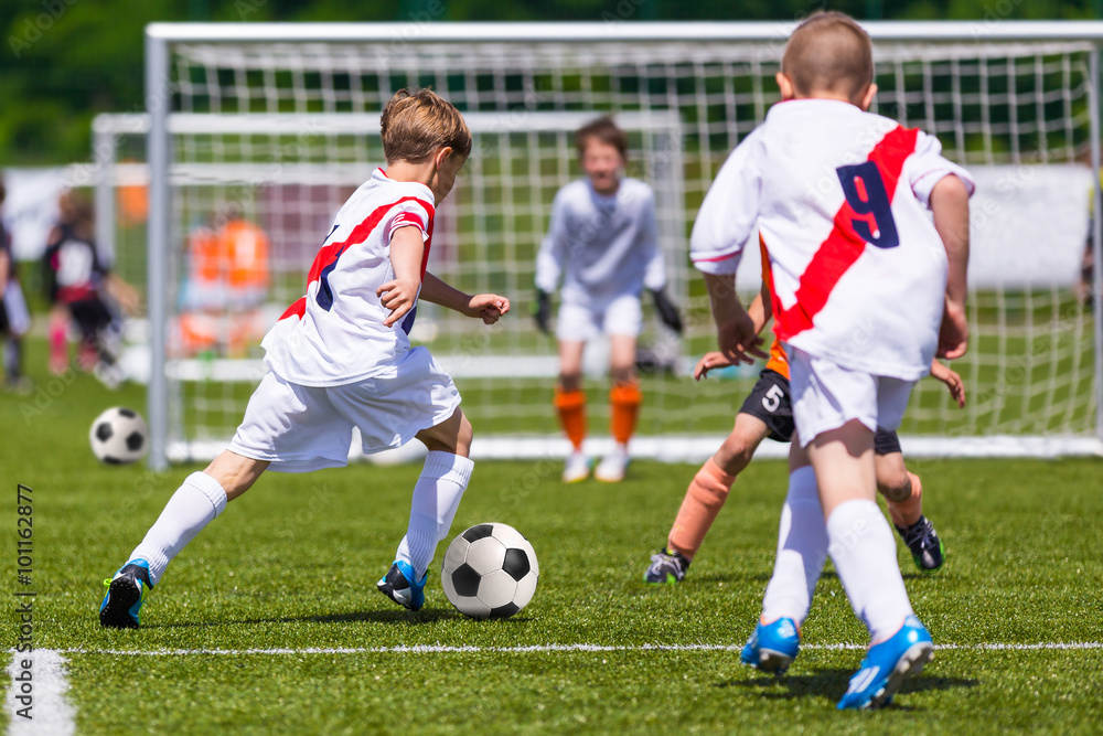 Fototapeta premium Training and football match between youth soccer teams. Young boys playing soccer game. Hard competition between players running and kicking soccer ball. Final game of football tournament for kids.