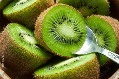 Juicy ripe kiwi fruit in wooden bowl with spoon