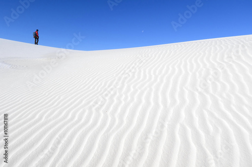 Photographer walking on white sand dunes, White Sands National Monument, New Mexico photo