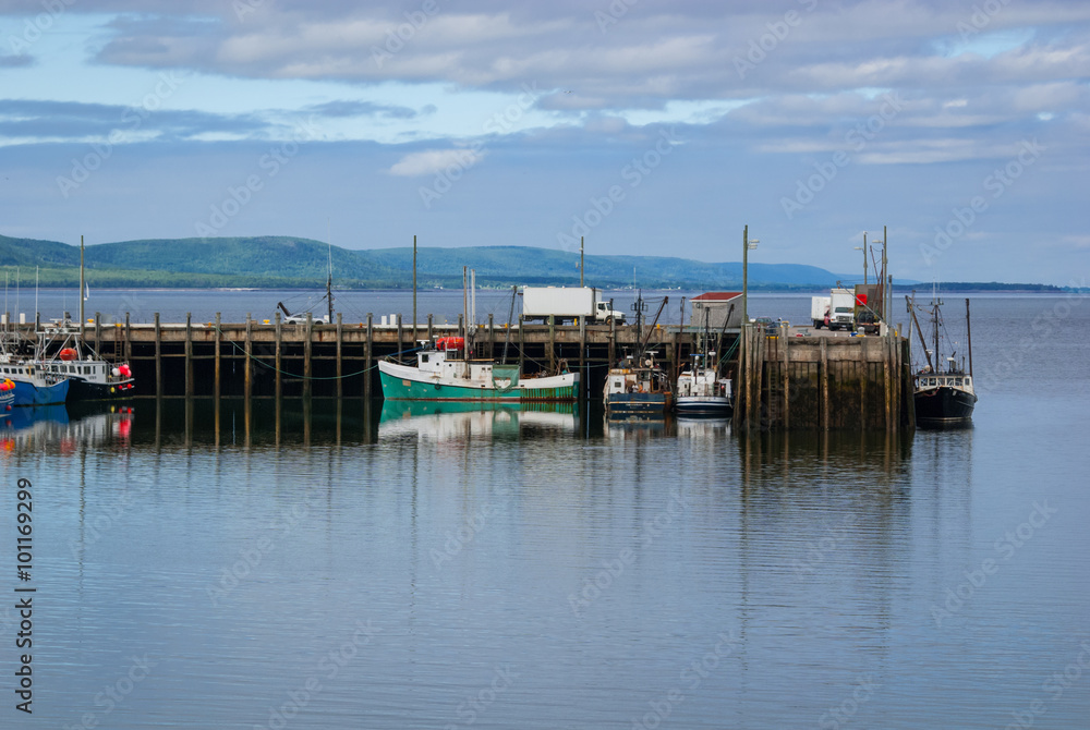 Fishing boats in the harbour at low tide in Digby, Nova Scotia.  Late spring afternoon with evening approaching.   Boats tied up, in for the day.  Sunshine on calm coastal water.