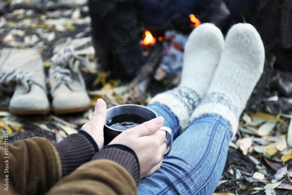 Woman sitting beside the fire with a cup of coffee Woman sitting beside the fire with a cup of coffee
