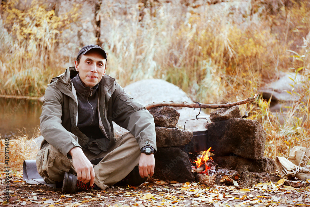 Fototapeta premium Man sitting beside fireplace outdoor