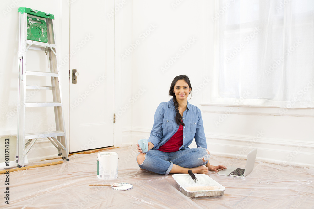 Mixed race woman relaxing while painting room Mixed race woman relaxing while painting room
