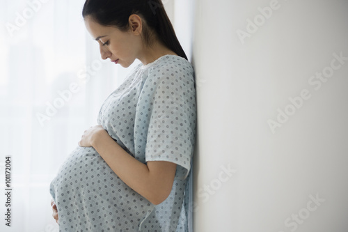Pregnant Caucasian woman holding her belly in hospital