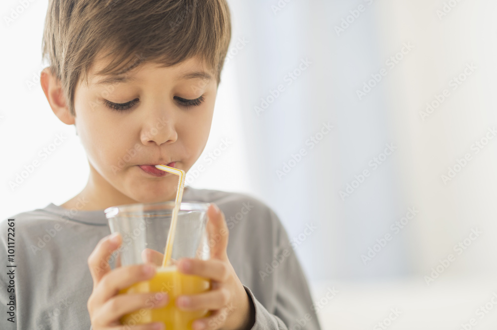 Hispanic boy drinking juice with straw Hispanic boy drinking juice with straw