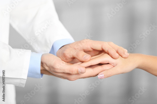 Hand of medical doctor carefully holding patient's hands
