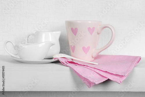 Tableware with pink cup and napkin on a white background