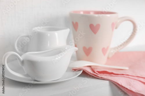 Tableware with pink cup and napkin on a white background, close up