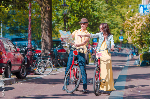 Photography Young tourists couple looking at map with bikes in european city