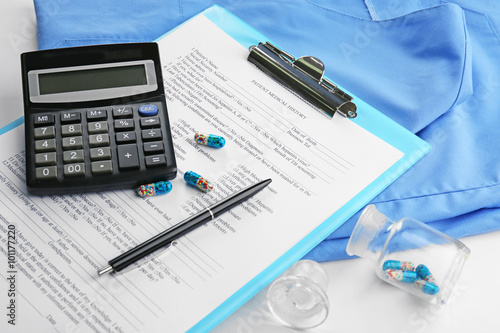 A stethoscope, coat, calculator and clipboard, close-up