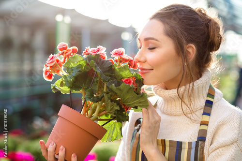 Inspired woman florist smelling flowers of begonia in greenhouse photo