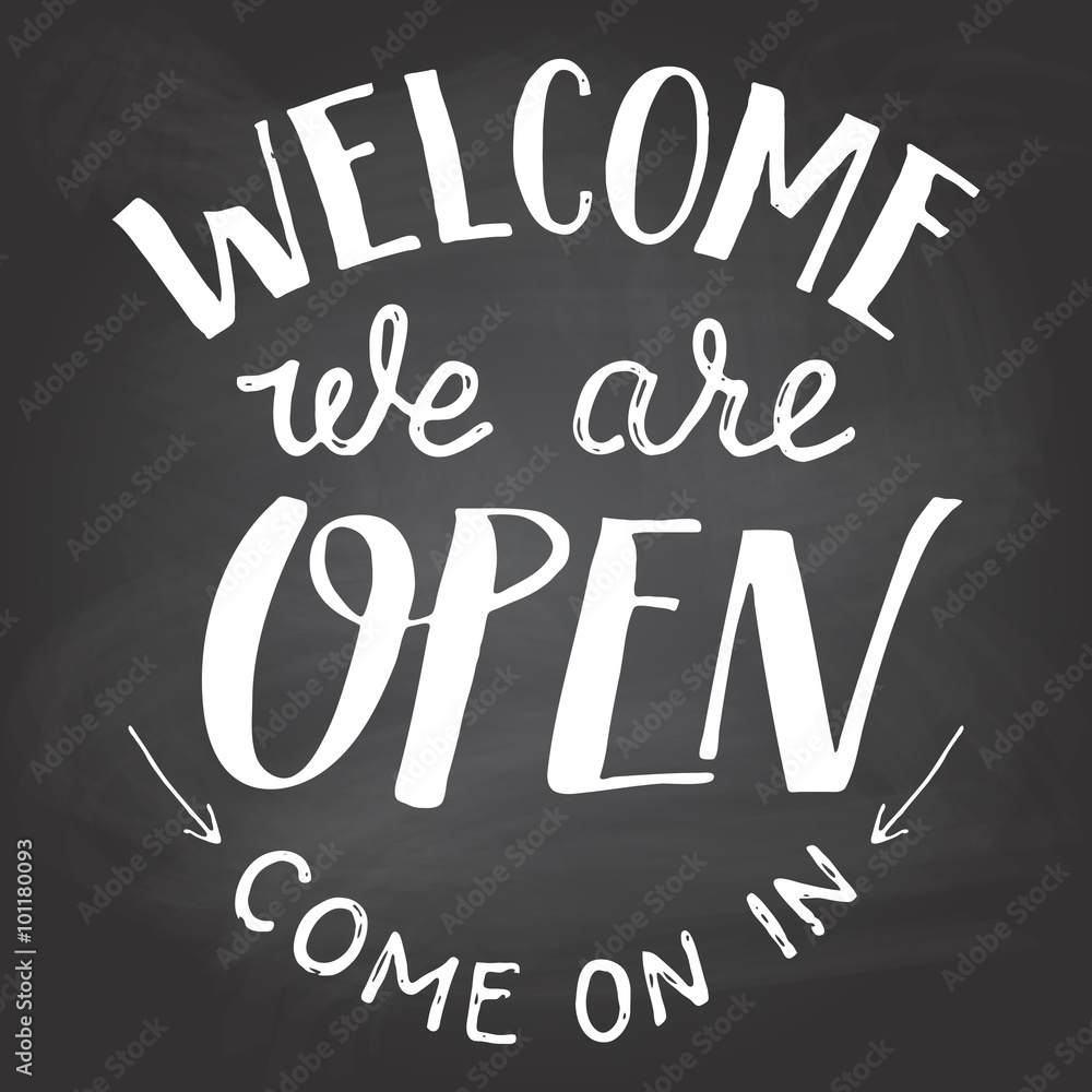 Welcome we are open. A welcome sign for cafes or shop visitors on blackboard background with chalk. Hand lettering