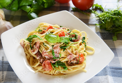 Spaghetti pasta with rucola, cherry tomatoes and prosciutto ham