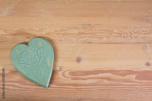 A green wooden heart on a natural wooden table