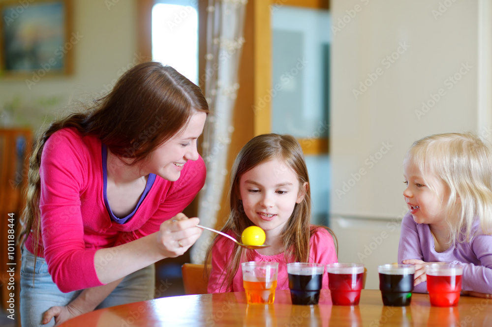 Young mother and her two daughters painting Easter eggs Young mother and her two daughters painting Easter eggs