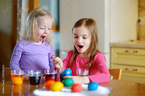 Two little sisters painting colorful Easter eggs