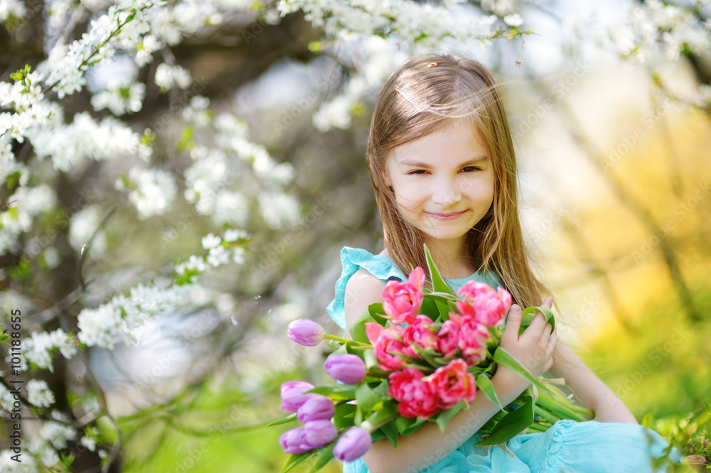 Adorable little girl holding tulips for her mother in cherry garden Adorable little girl holding tulips for her mother in cherry garden