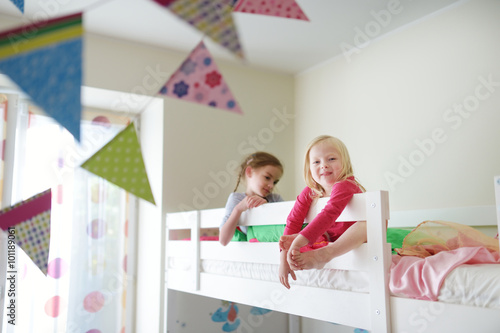 Two little sisters fooling around, playing and having fun in twin bunk bed