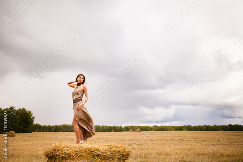 Молодая красивая девушка стоит на стоге сена