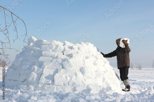 The man  building an igloo on a snow glade in the winter