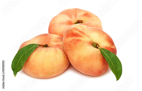 Three whole flat peaches with green leaves (isolated)