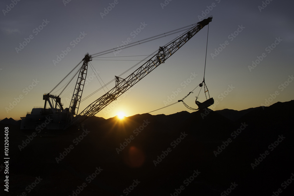 silhouette of drag line working on mine at sunrise with beautifu