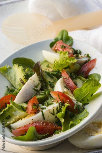 Pflücksalat mit Avocado, Tomaten und Eiern auf einer ovalen Schale mit Salatbesteck