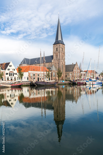 Saint Michaels Church and historic houses on quay of Zuiderhaven harbour canal with boats in Harlingen, Friesland, Netherlands
