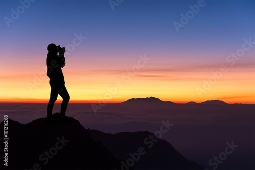 silhouette of woman taking photograph on the top of mountain and