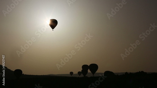 Balloon silhouette floats over Cappadocia rocks at evening-glow, Turkey