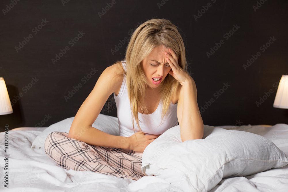 Woman in menstrual pain sitting in bed Woman in menstrual pain sitting in bed