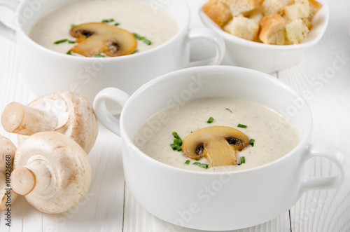 Mushroom cream soup in two white bowls with croutons and champig photo