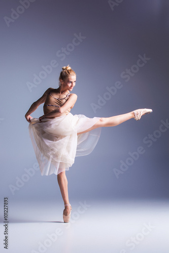 Young beautiful modern style dancer posing on a studio background
