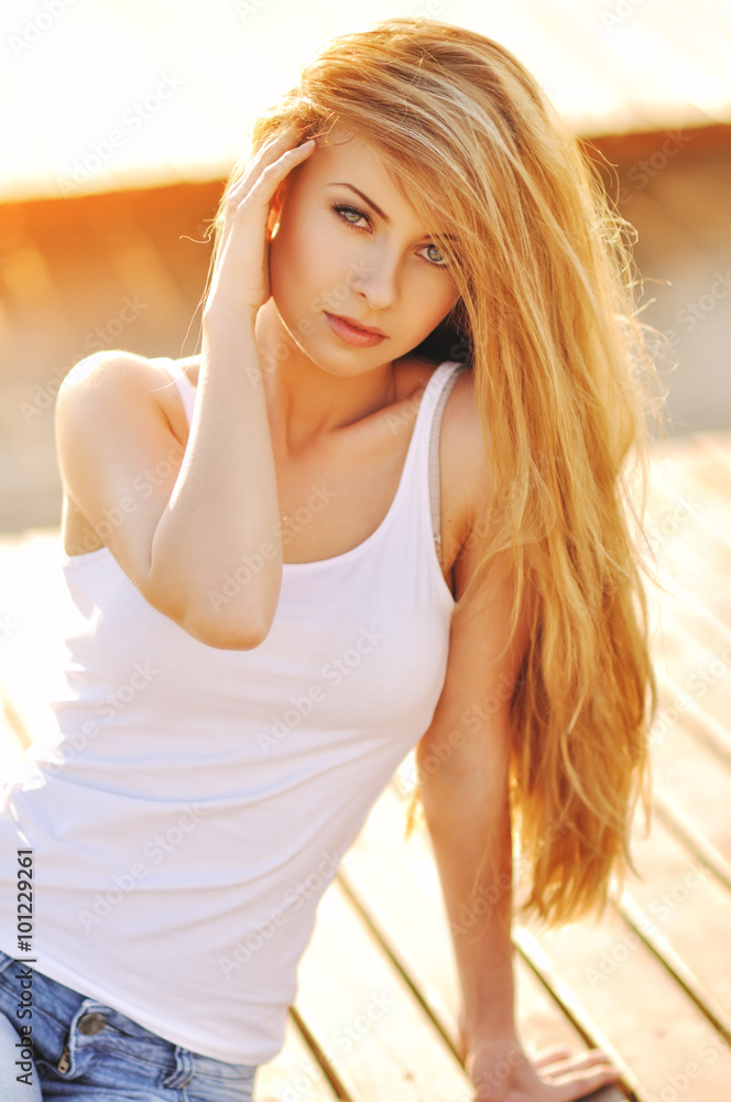 Portrait of a beautiful woman with magnificent hair in a white top and stylish jeans
