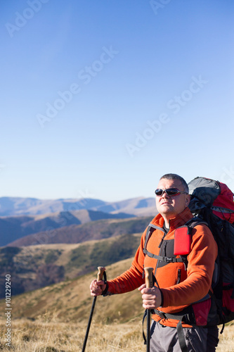 Man hiking in the mountains with a backpack and tent.